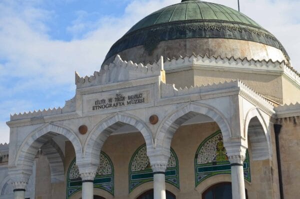 Exterior view of the Ethnography Museum of Ankara featuring arched white marble entrance, decorative details, and a large green dome.