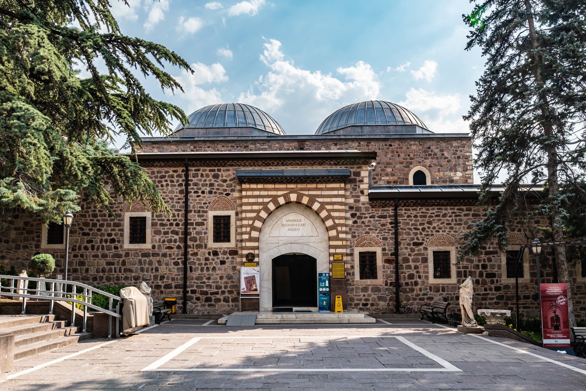 A historic stone building with domed roofs, labeled "Ankara Rahmi M. Koç Museum," surrounded by trees and entrance steps.